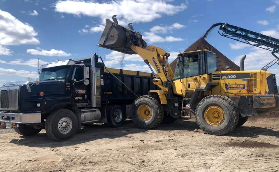 Person at Poupart Excation loading top soil to deliver it to a customer