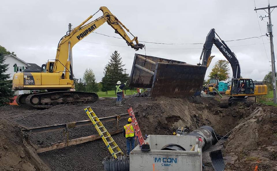Workers at Poupart Excavation installing a Trench Box